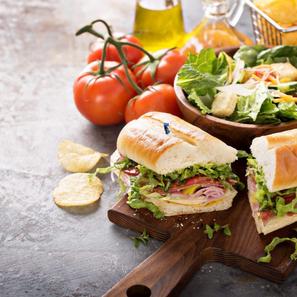 Italian sub sandwich with salami, ham and caesar salad