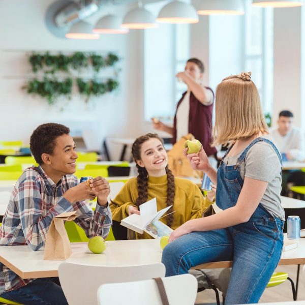 happy high school students taking lunch together at school cafeteria