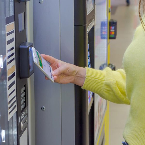 Close up view of woman paying for purchase at snack vending mach